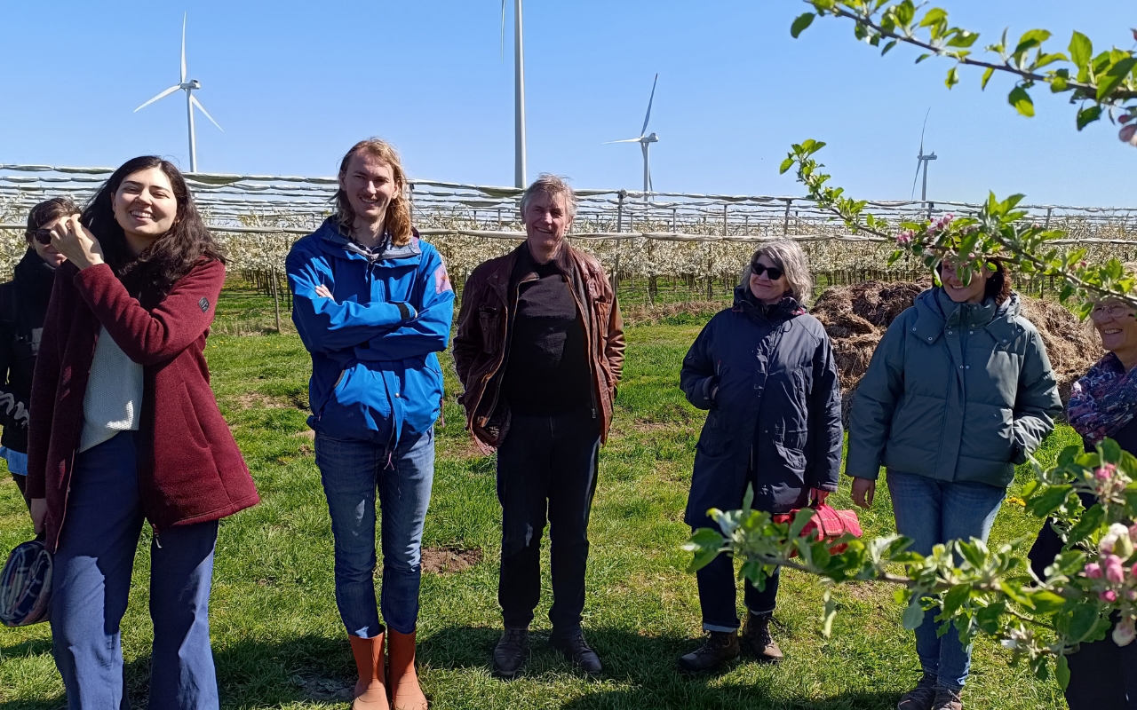 Team von Munder + Erzepky bei der Hofführung auf dem Bio-Obsthof Feldmann in Francop – blühende Apfelbäume und Windräder im Hintergrund, Altes Land Hamburg
