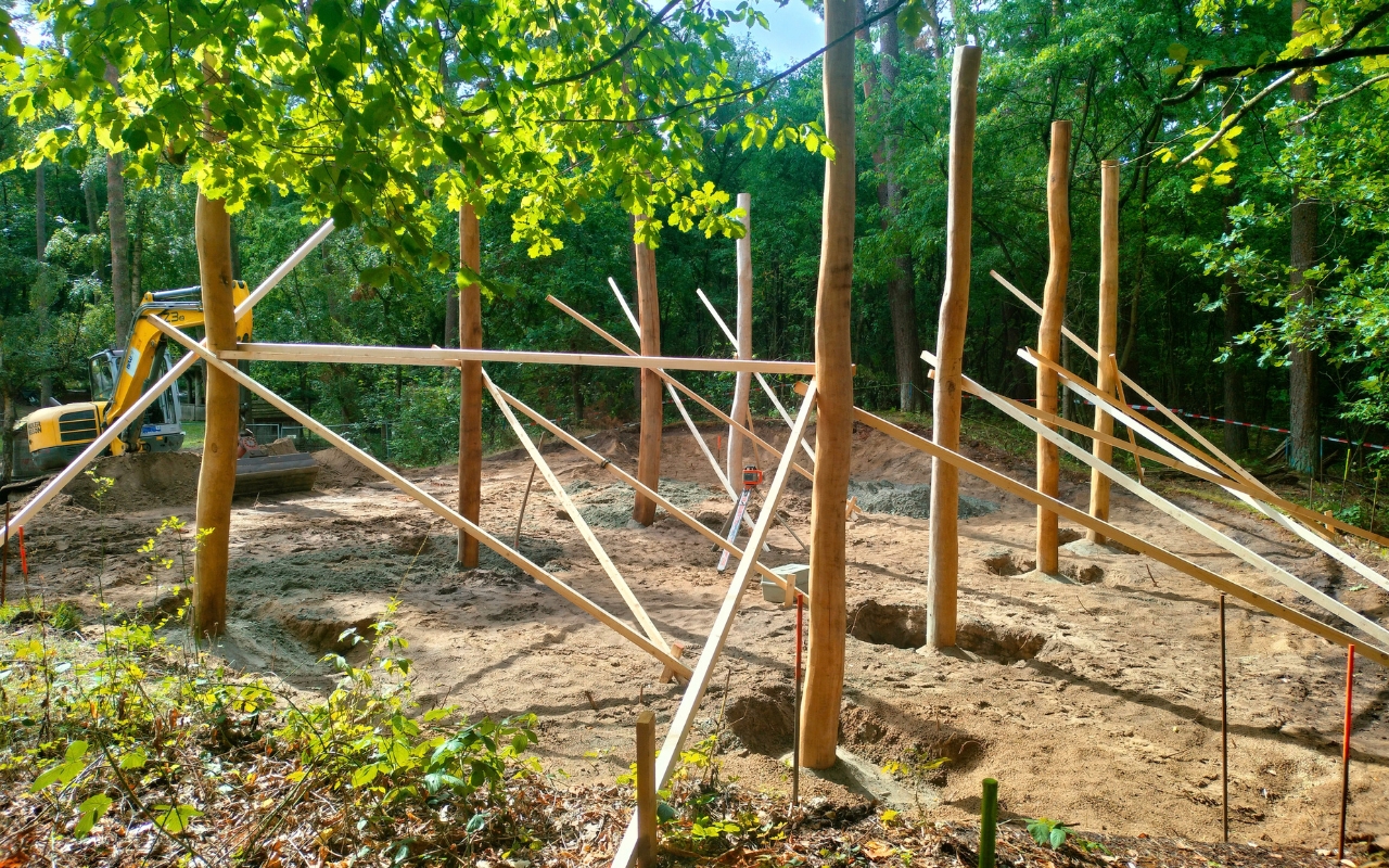 Neue Holzpfosten und Bagger auf der Baustelle des Waldspielplatzes Klövensteen in Hamburg-Rissen